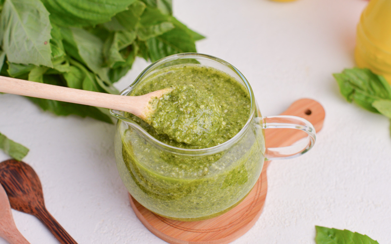 wooden spoon in jar of basil pesto sauce