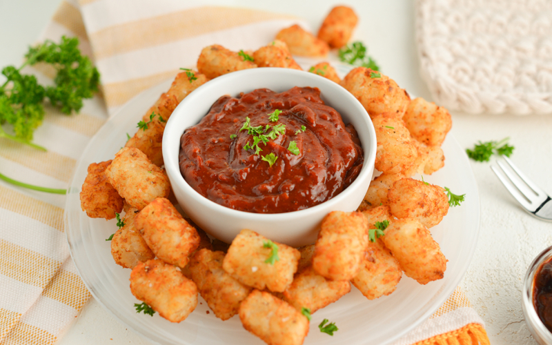 chipotle ketchup in a bowl surrounded by tater tots