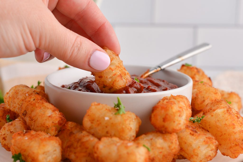 straight on shot of tater tot dipped into chipotle ketchup