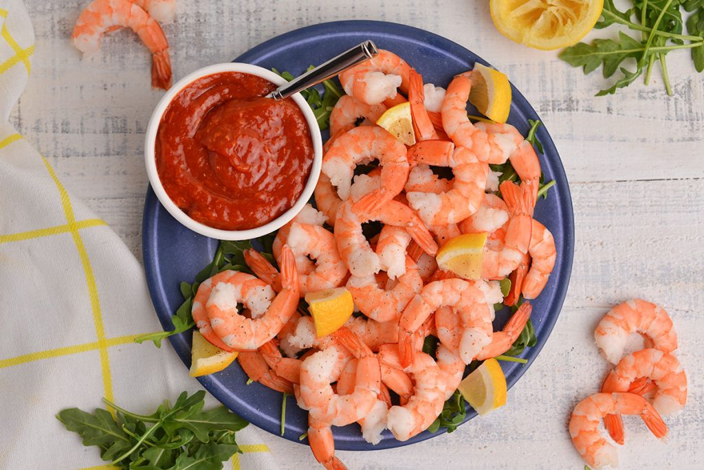 plate of shrimp with a bowl of cocktail sauce