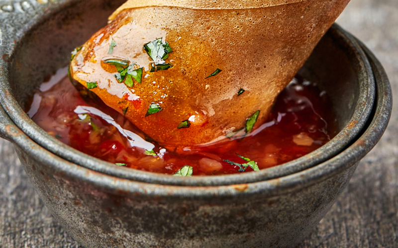 egg roll dipping into sweet thai chili sauce