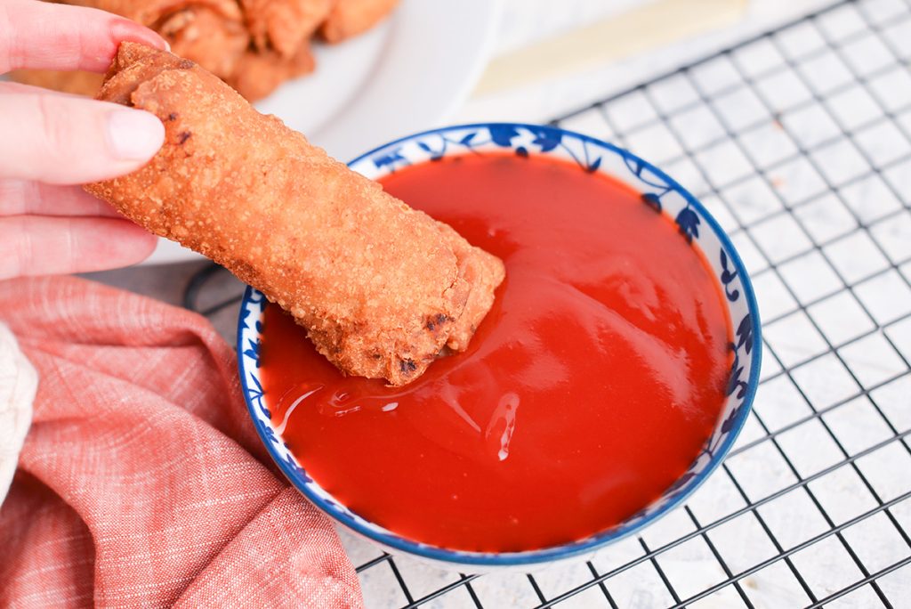 egg roll dipped into sweet and sour sauce