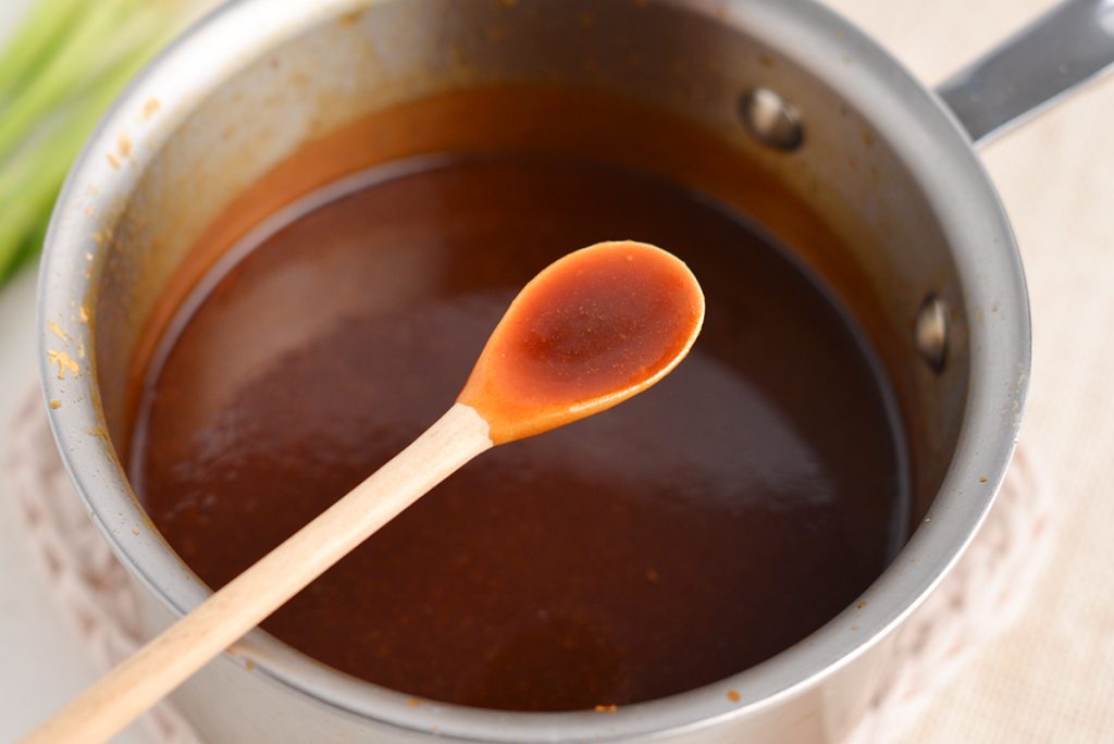 spoon with teriyaki sauce over pot