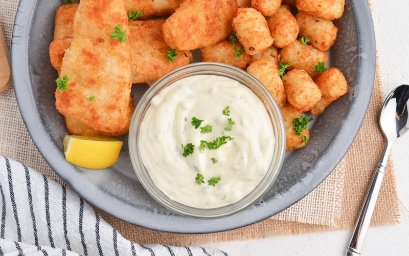 overhead shot of bowl of tartar sauce on plate of fish