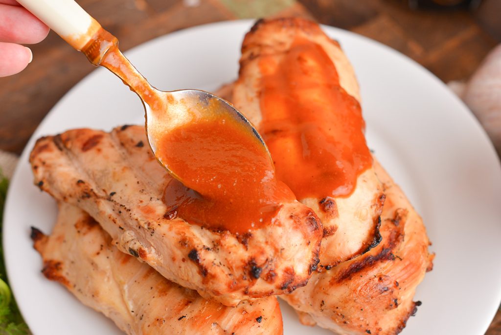 spoon pouring beer bqq sauce on chicken