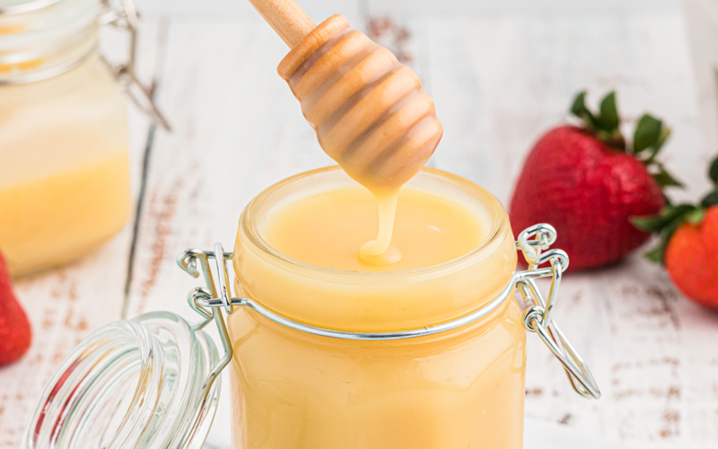 spoon dipping into jar of blond syrup