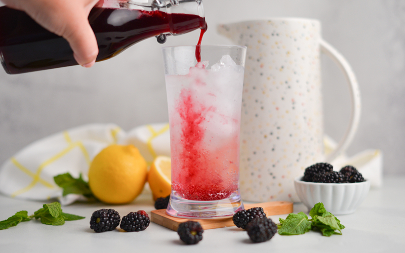 blackberry simple syrup poured into cocktail