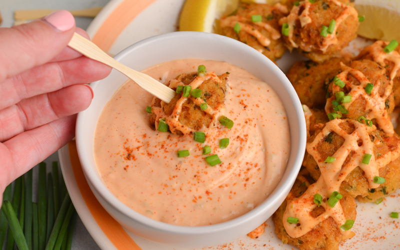 crab cake dipping into crab cake sauce