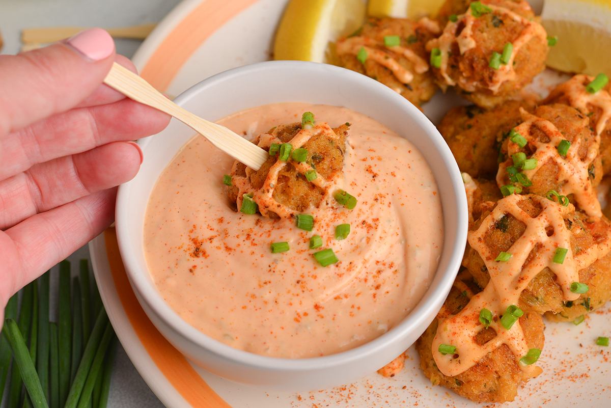 crab cake dipping into crab cake sauce