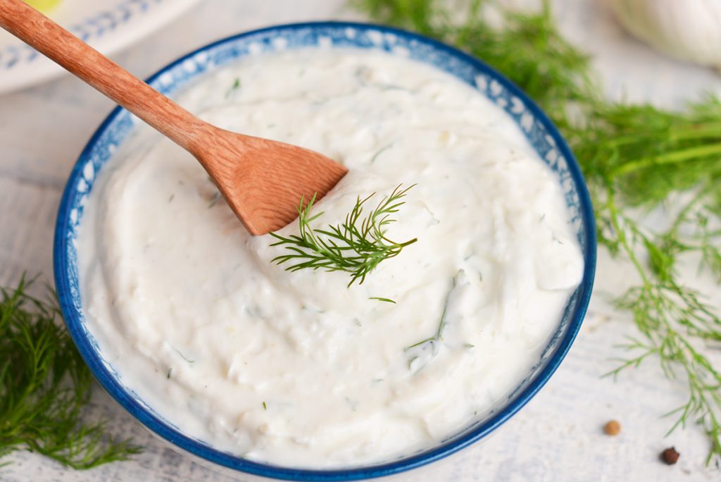 wooden spoon in bowl of dill sauce