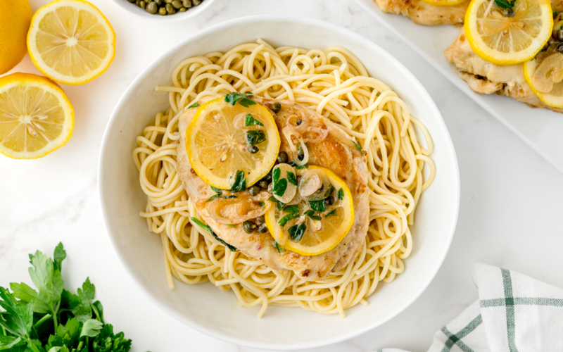 overhead shot of piccata sauce over chicken and pasta