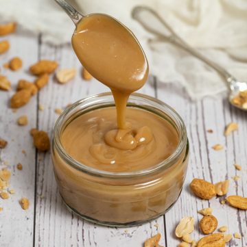 spoon pouring peanut butter sauce in jar