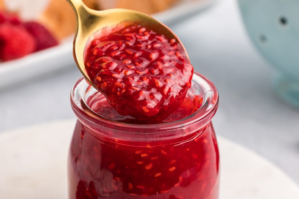 close up of spoon dipping into raspberry sauce