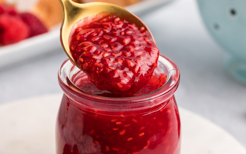 close up of spoon dipping into raspberry sauce