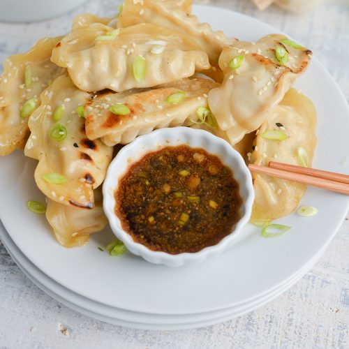 bowl of pot sticker sauce on plate of pot stickers