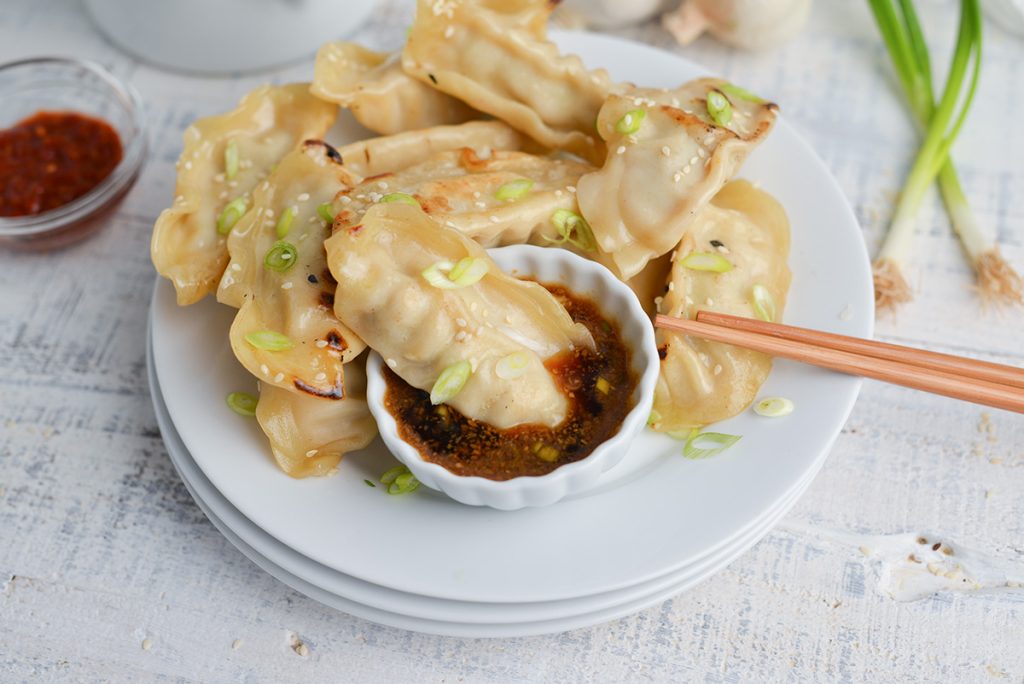 pot sticker dipping into bowl of sauce