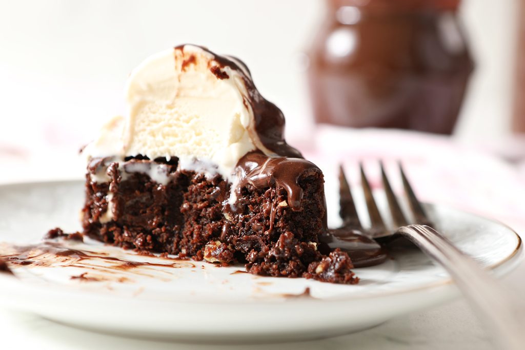 slice of chocolate cake topped with ice cream and chocolate sauce