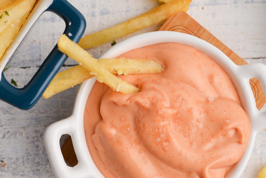 close up of two fries in bowl of sauce