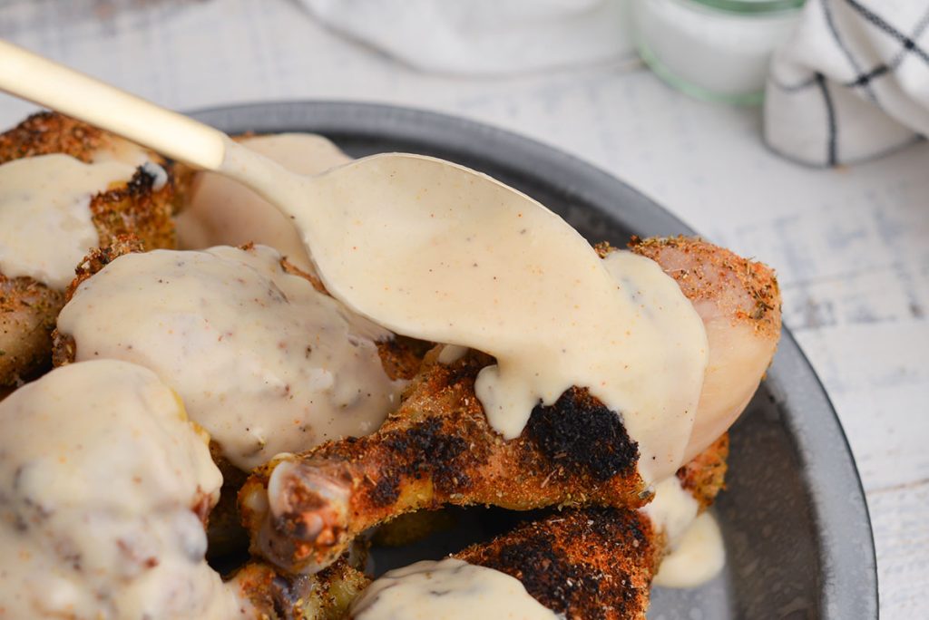 spoon pouring alabama white sauce onto chicken