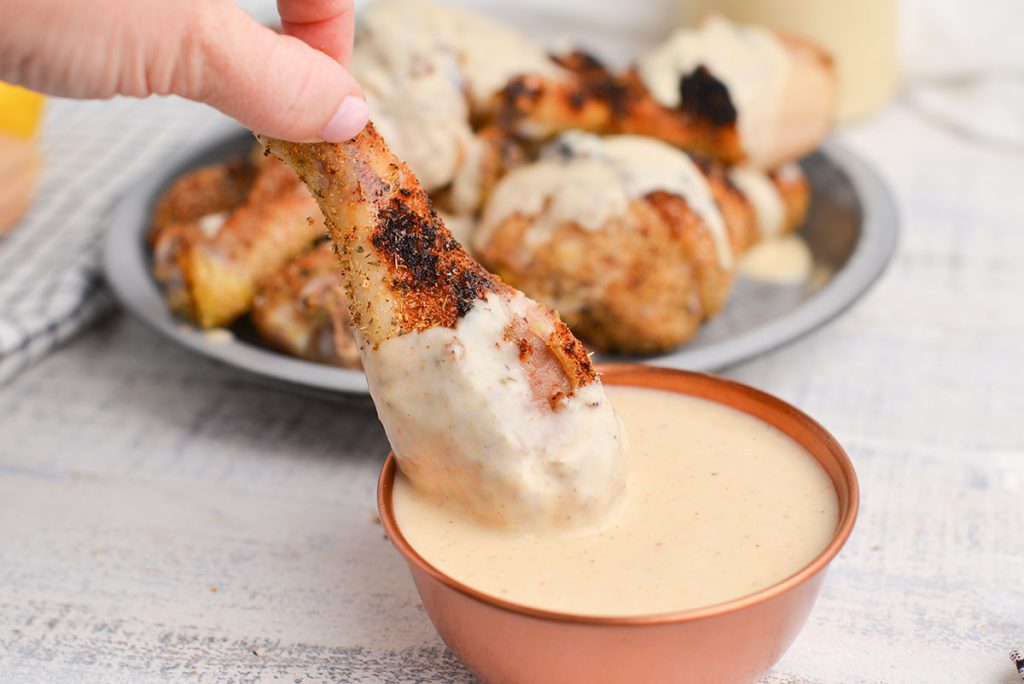 chicken drumstick dipping into white bbq sauce