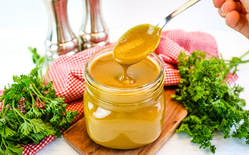 spoon in jar of golden bbq sauce