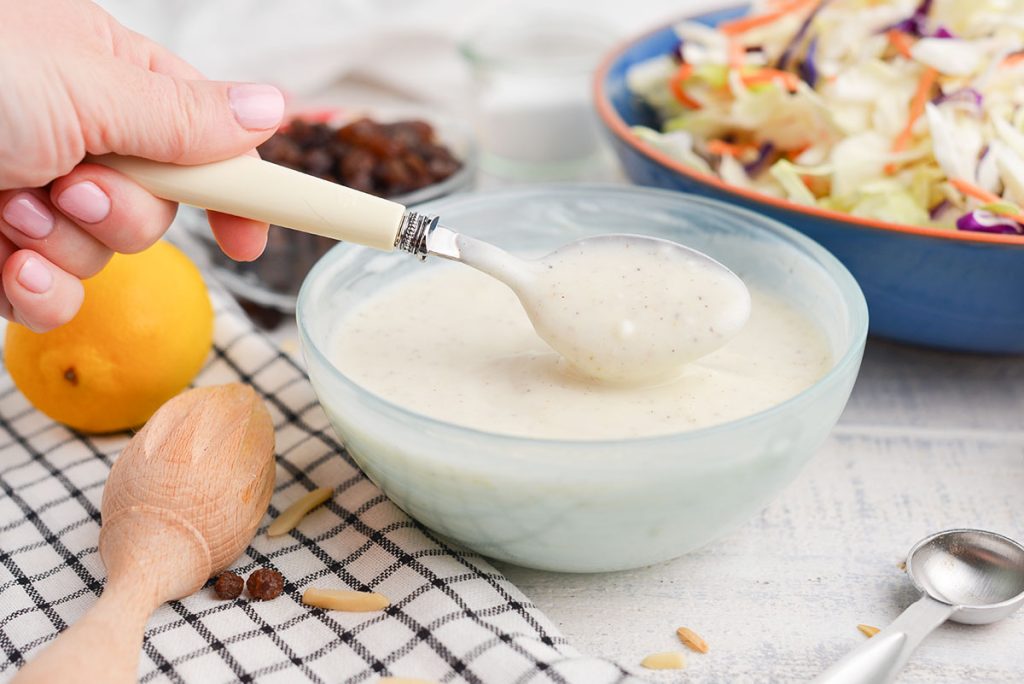 spoon in bowl of coleslaw dressing