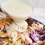 coleslaw dressing poured into coleslaw mix
