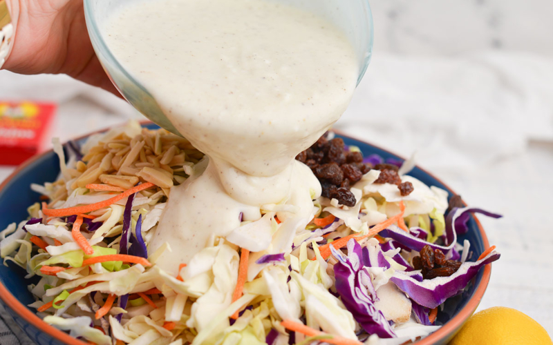 coleslaw dressing poured into coleslaw mix