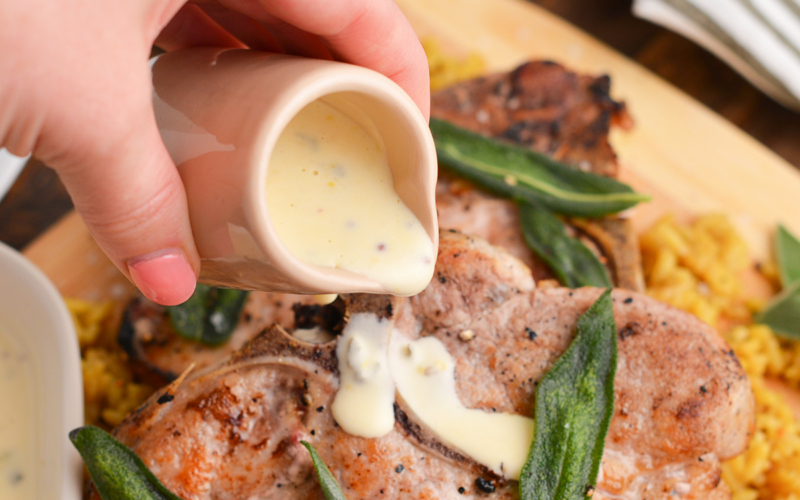 hand pouring mustard sauce onto steak