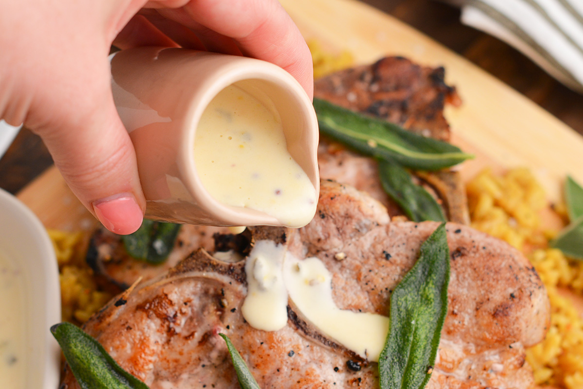 hand pouring mustard sauce onto steak