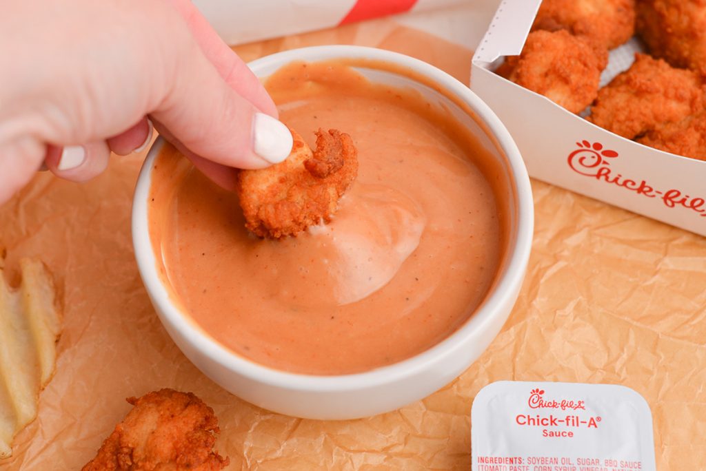 chicken nugget dipping into bowl of sauce