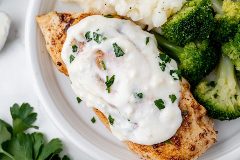 overhead shot of chicken topped with white garlic sauce