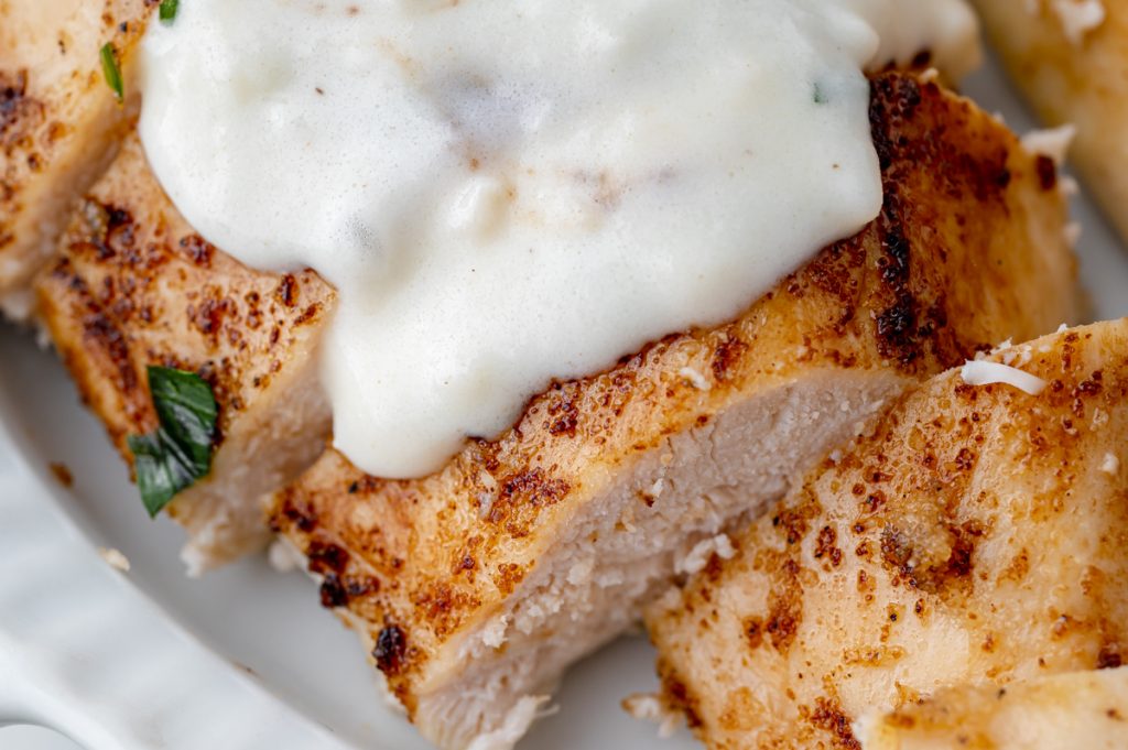 close up of sliced chicken topped with cream sauce