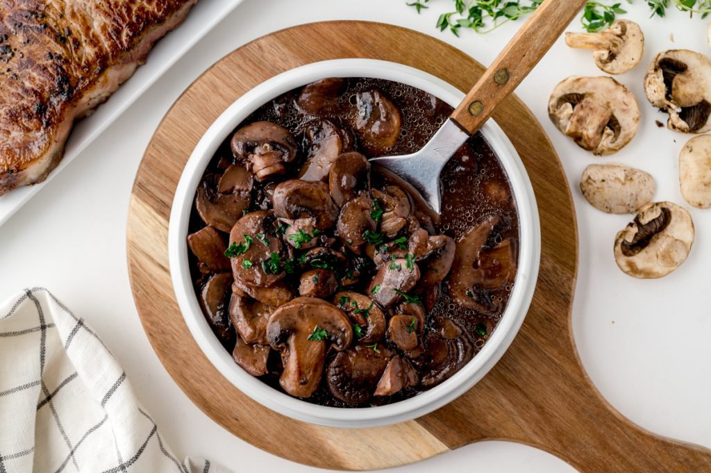 overhead shot of bowl of red wine mushroom sauce with spoon in it