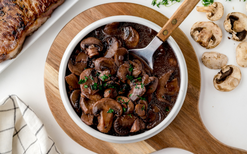 overhead shot of bowl of red wine mushroom sauce with spoon in it