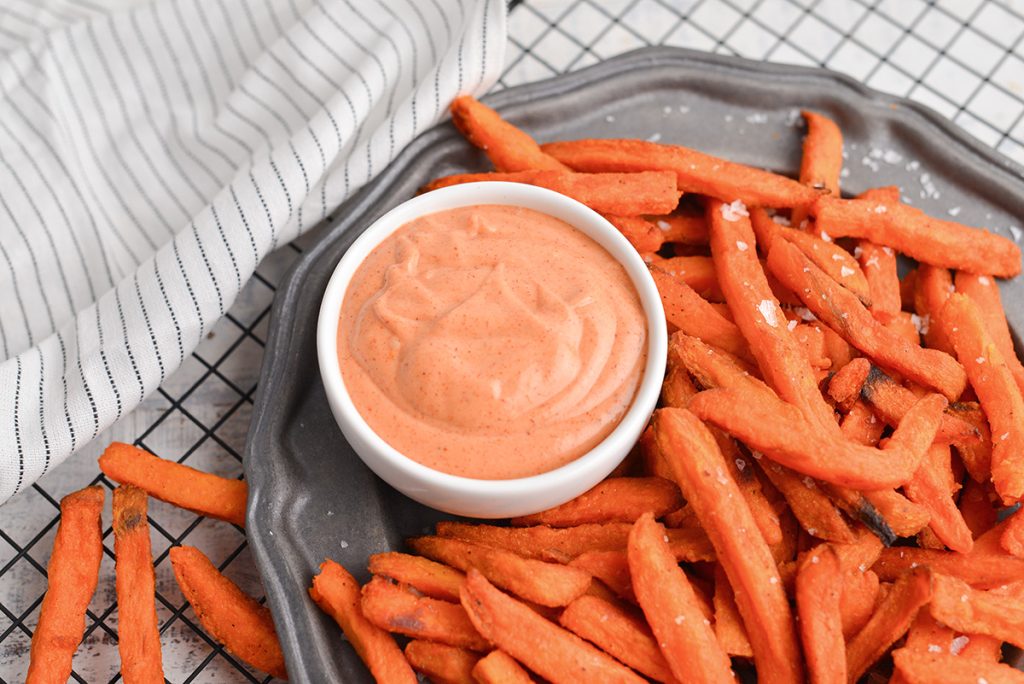 angled shot of bowl of sweet potato fry dipping sauce with sweet potato fries