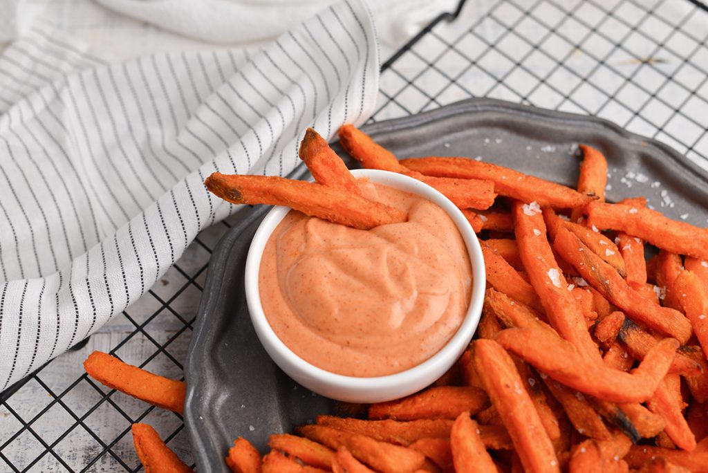 two sweet potato fries in bowl of sauce