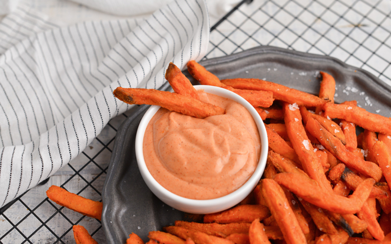 two sweet potato fries in bowl of sauce