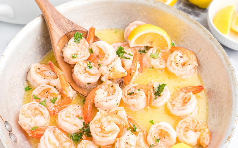 wooden spoon in pan of shrimp scampi sauce