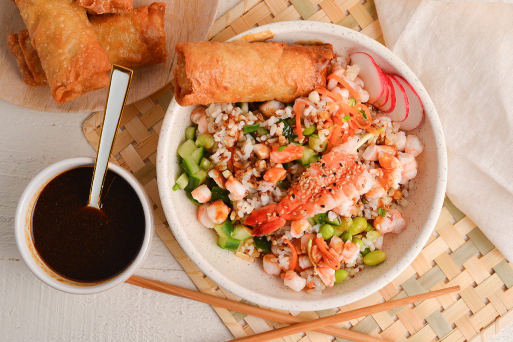 overhead shot of egg roll on sushi bowl with sauce