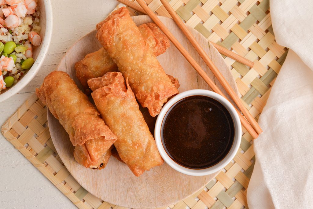 overhead shot of plate of egg rolls with sauce
