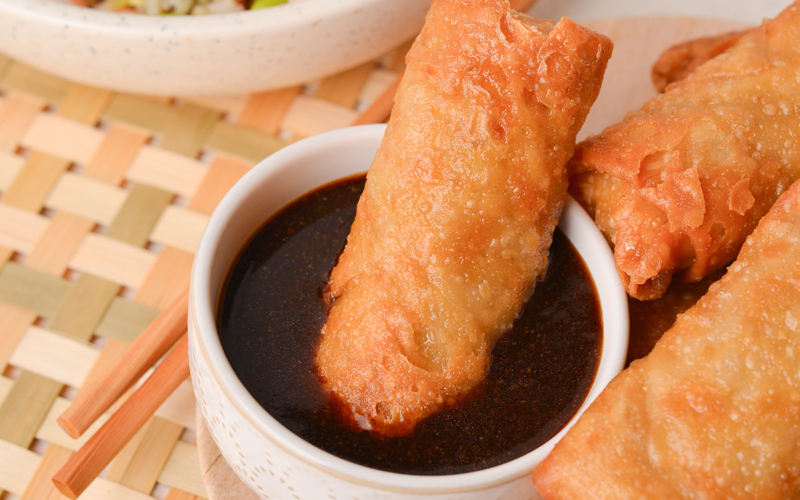 egg roll in bowl of sauce