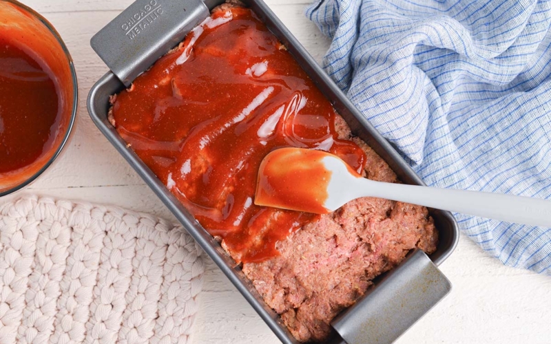 overhead shot of glaze spread over raw meatloaf