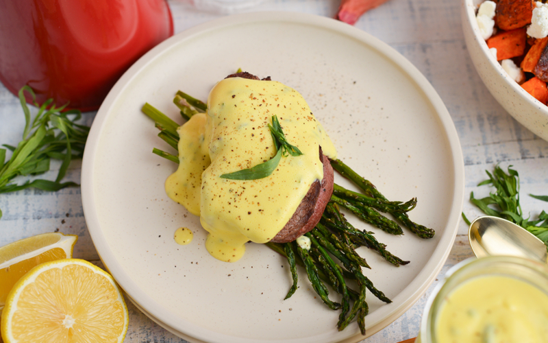 angled shot of creamy sauce over steak and asparagus