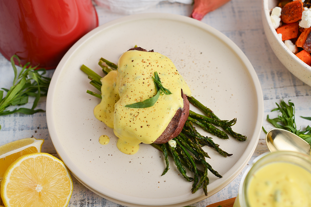 angled shot of creamy sauce over steak and asparagus