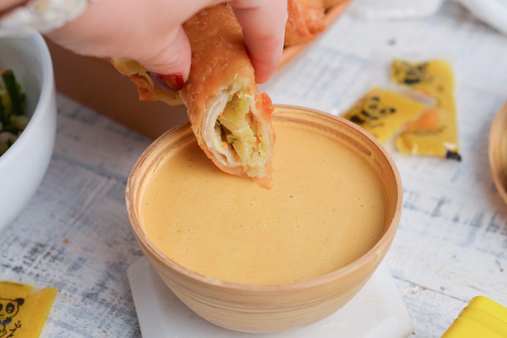 hand dipping egg roll in chinese hot mustard