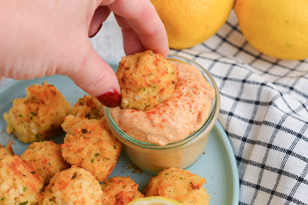 crab cake dipping into remoulade sauce