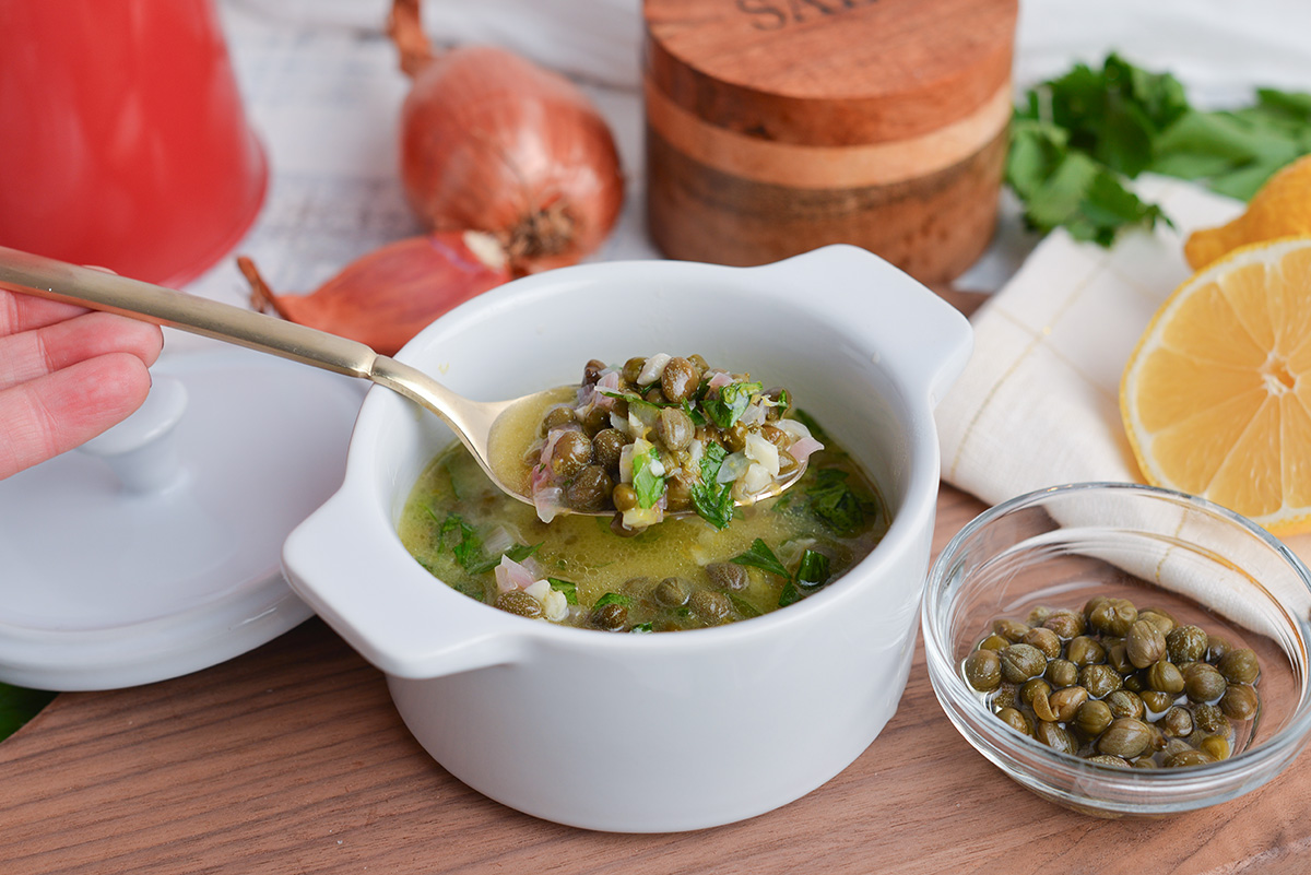 angled shot of spoon in bowl of lemon caper sauce