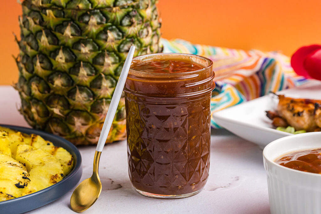 straight on shot of spoon leaning against jar of huli huli sauce