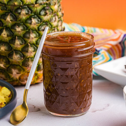 straight on shot of spoon leaning against jar of huli huli sauce
